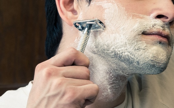 man shaving with straight razor